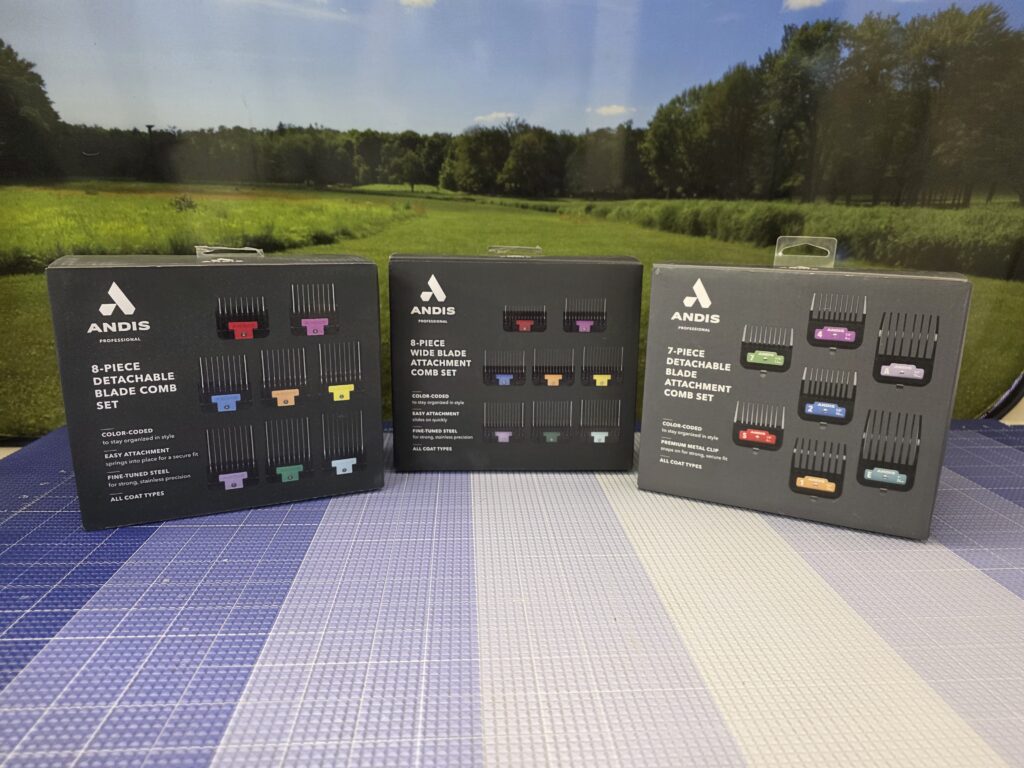 Three boxed sets of color-coded Andis detachable clipper guard combs on a grooming table