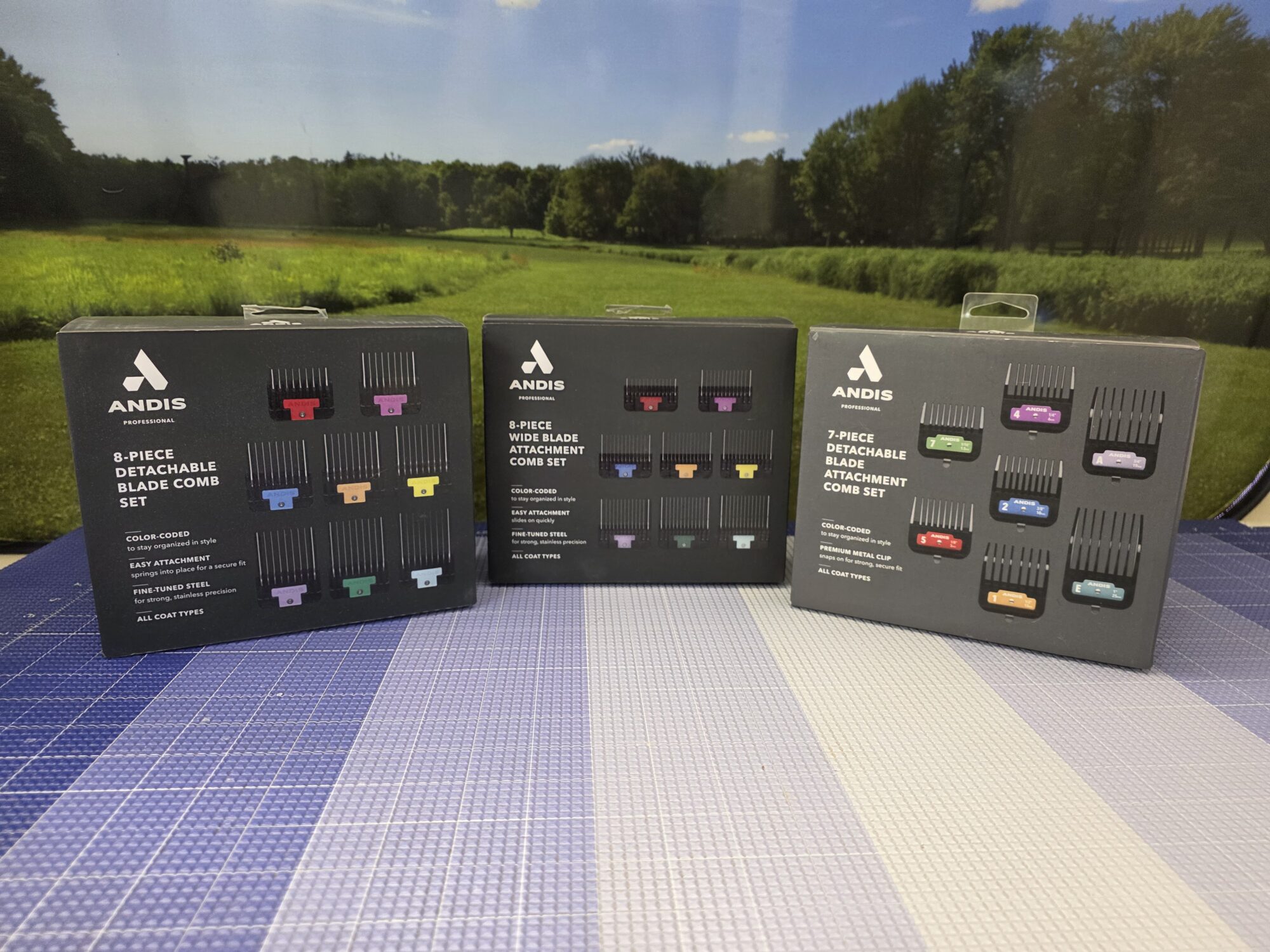 Three boxed sets of color-coded Andis detachable clipper guard combs on a grooming table